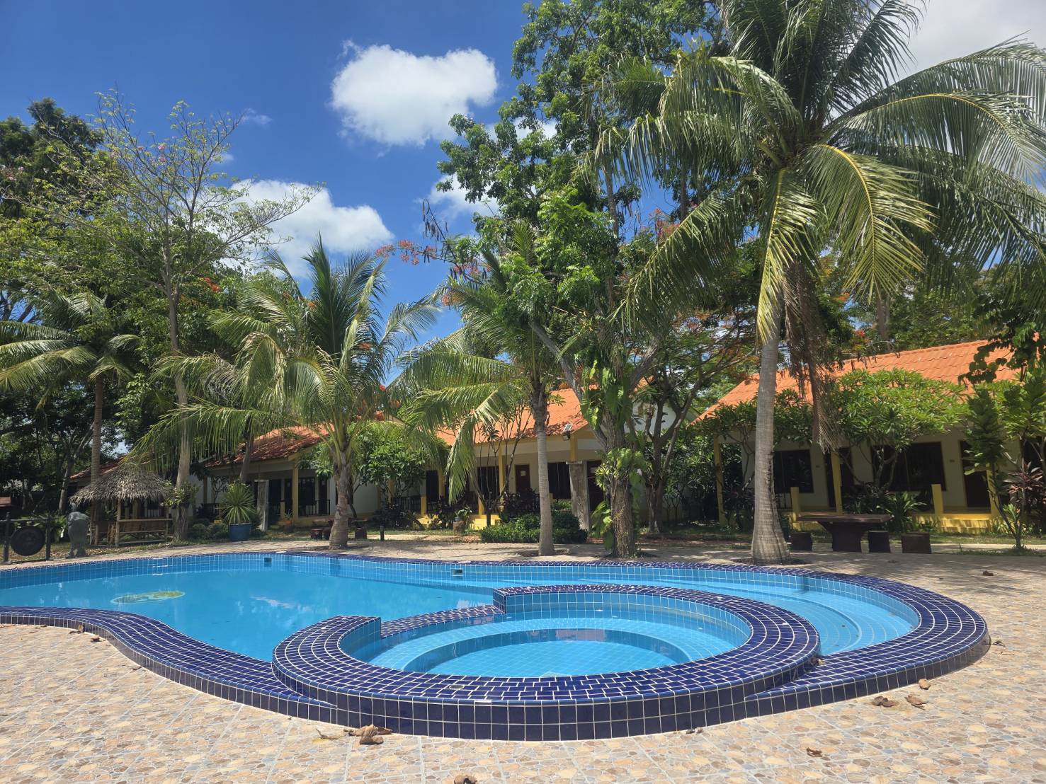A swimming pool among trees and guest buildings